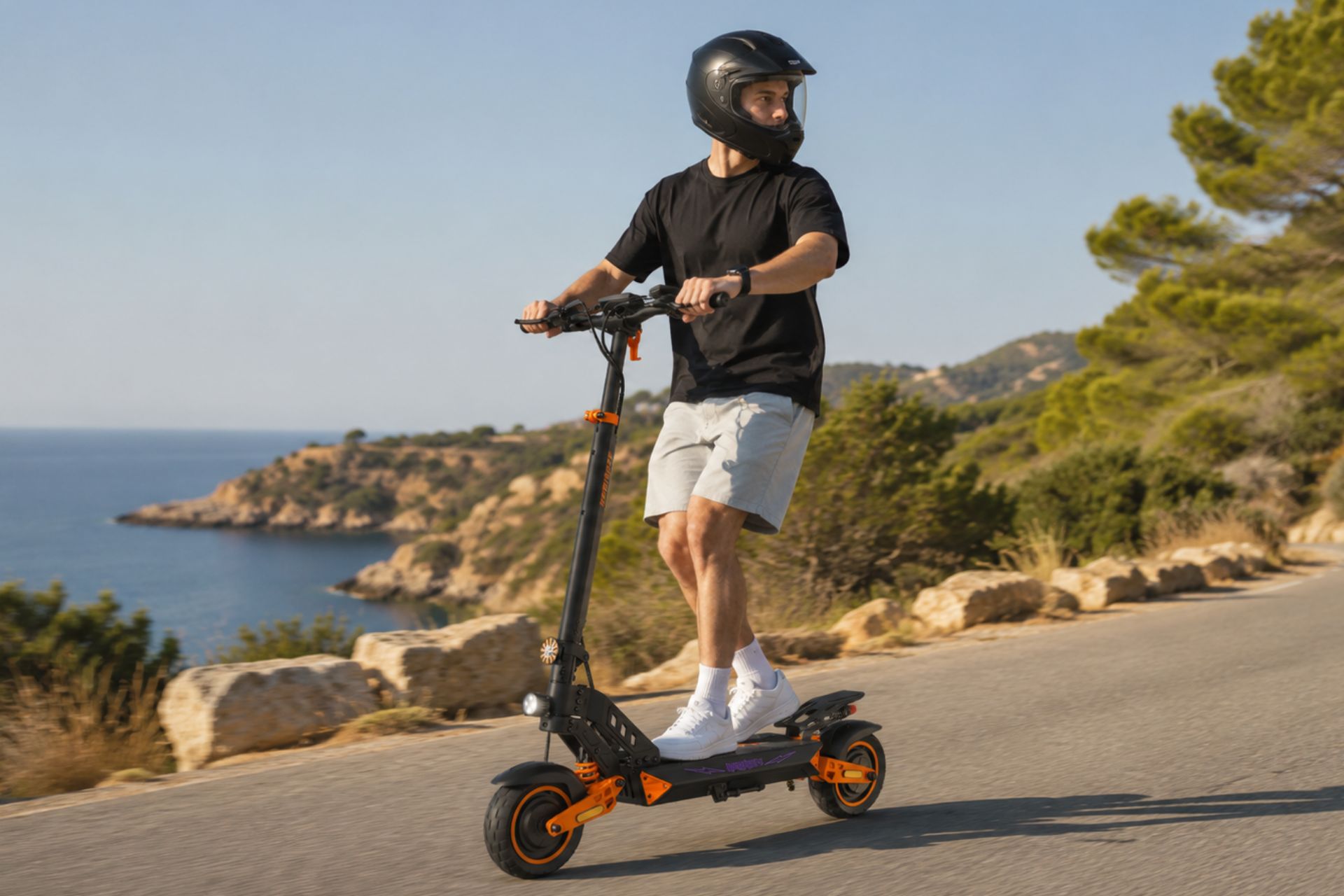 Un joven con casco integral conduciendo un patinete el&eacute;ctrico Kamikaze K1 Lite por un pueblo espa&ntilde;ol.
